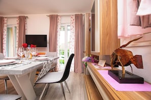 A dining area with a table set for two, a television mounted on the wall, and a decorative sculpture on a side table. - Apartments Baradic (Zadar)