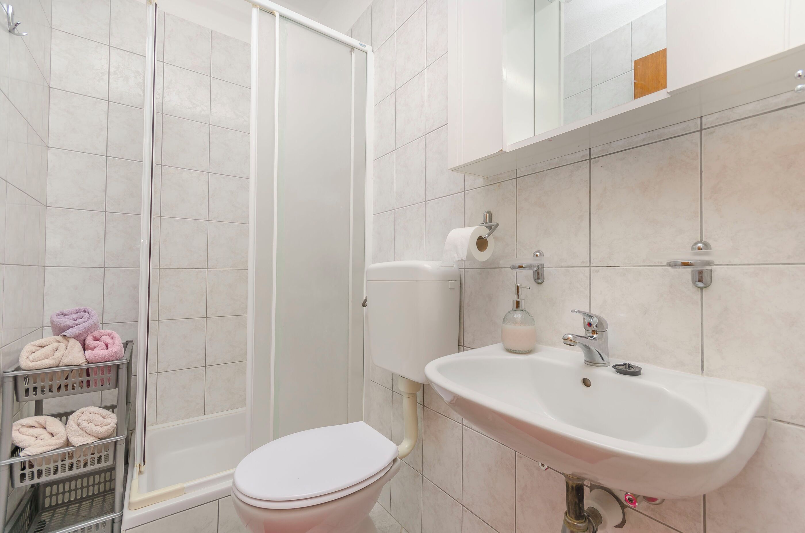 Un baño con inodoro, lavamanos y ducha. Hay toallas en un tendedero.