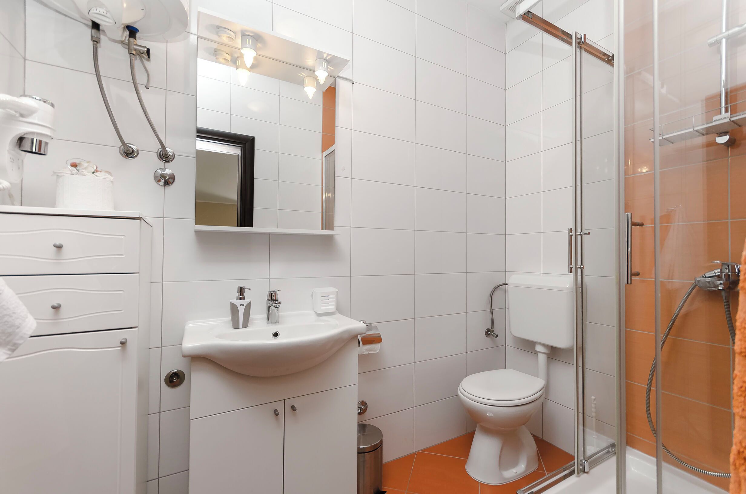 A modern bathroom with a white sink, toilet, and glass shower enclosure.