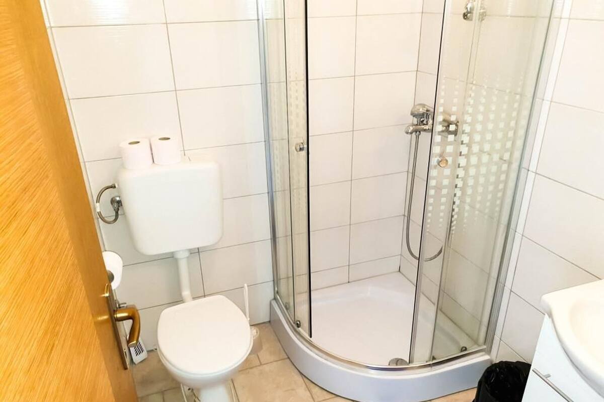A bathroom with a toilet, a glass-enclosed shower, and a white sink.