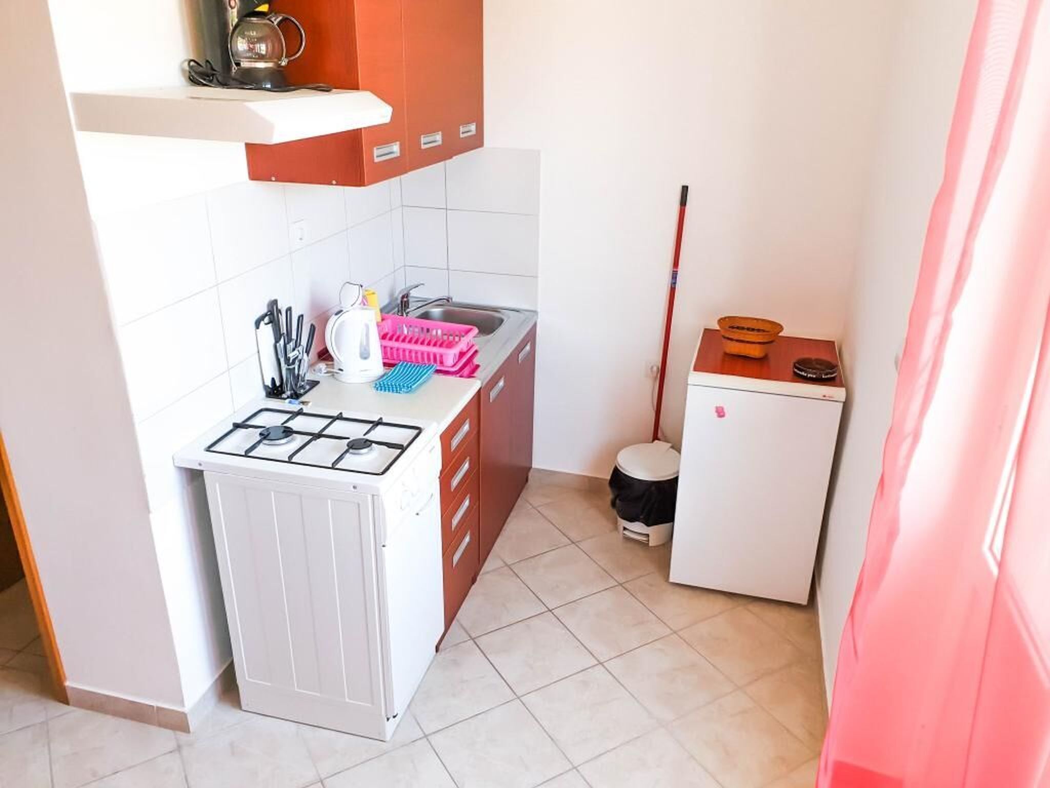 A compact kitchen with a gas stove, sink, and a small refrigerator.