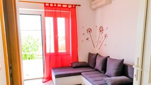 Una sala de estar moderna con un sofá seccional, una cortina roja y una decoración de diente de león en la pared.