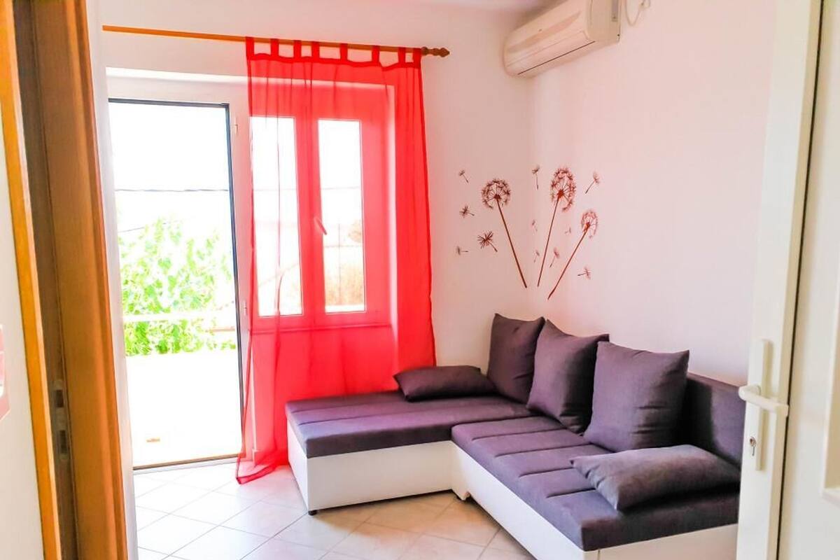 A modern living room with a sectional sofa, a red curtain, and a wall decoration of dandelions.