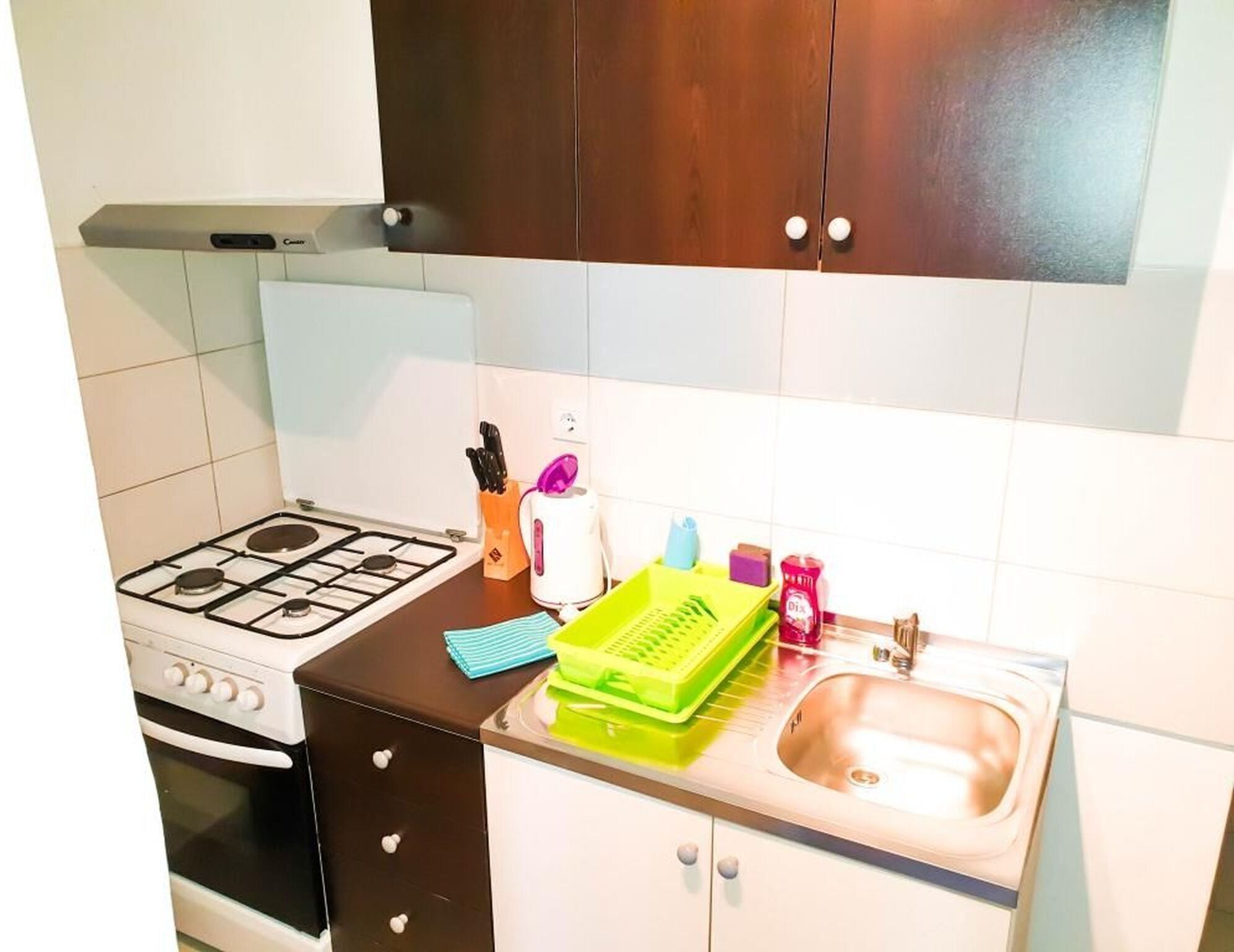 Kompakti keittiö, jossa on kaasuliesi, sisäänrakennettu uuni, pesuallas ja työtaso, jonka päällä on erilaisia keittiötarvikkeita.