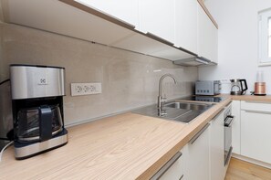 A modern kitchen with a coffee maker, microwave, toaster, and espresso machine. - Apartments and Room Kate (Tisno)