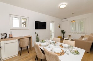 Un salon moderne comprenant un coin repas, un téléviseur à écran plat fixé au mur et un canapé.