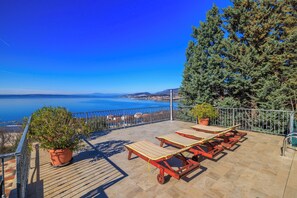A terrace with lounge chairs and potted plants, overlooking a coastal view. - Apartment Marijana (Novi Vinodolski)