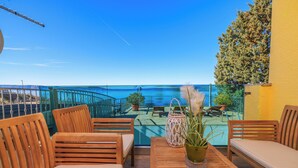 Eine Holzterrasse mit Sitzgelegenheiten und Blick aufs Meer.
