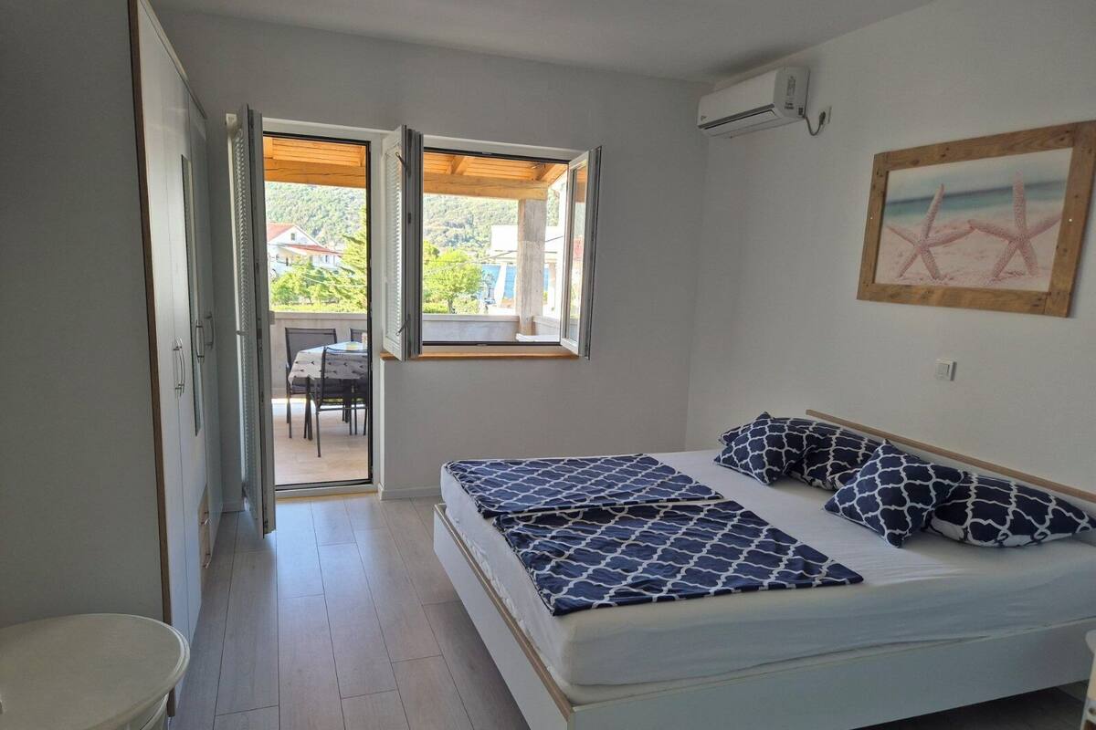 A bedroom with a bed, a small table, and a window with a view of the outside.