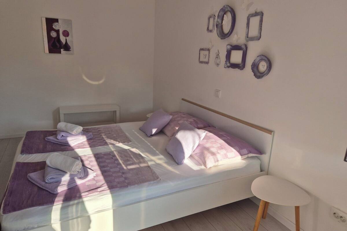A bedroom with a bed, pillows, a small table, and wall decorations.