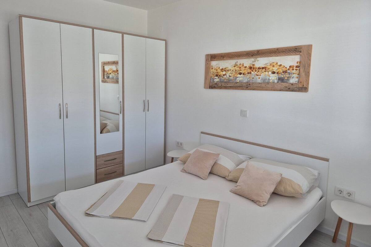 A bedroom with a bed, bedside tables, a wardrobe, and a painting on the wall.