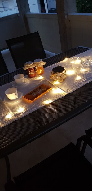 Ein Tisch gedeckt mit Kerzen, einer Laterne und einer Auswahl an Snacks, was auf eine gemütliche Essgelegenheit im Freien hindeutet.