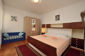 Un dormitorio con una cama, un armario de madera, un sofá azul y una alfombra roja.