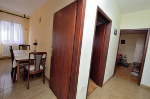 Un comedor con mesa y sillas, una puerta de madera y un pasillo que da a un dormitorio.