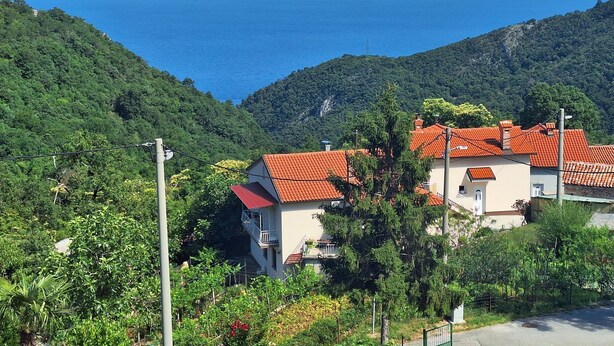 Un pueblo costero con casas escalonadas, una vista despejada del mar y abundante vegetación.