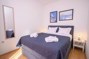 Ein Hotelzimmer mit einem Bett, zwei Kissen, einem Nachttisch mit Lampe und zwei Bildern an der Wand.