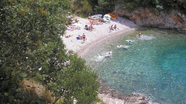 A beach with clear water, people swimming, and boats. - Apartment Orlic (Senj)