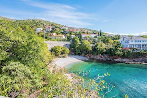 A coastal town with clear turquoise waters, dense greenery, and a mix of residential buildings. - Apartment Orlic (Senj)