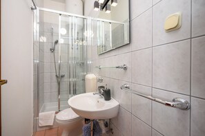 Ein modernes Badezimmer mit Duschkabine aus Glas, einem weißen Waschbecken und einer Toilette.