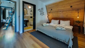 A modern bedroom with a wooden headboard, a large bed with a patterned bedspread, a bedside table with a lamp, and a wooden wall panel. - Villa Bellis (Mrkopalj)