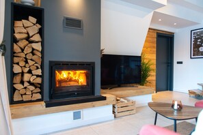 A modern living room with a fireplace, a television, and a wooden bench. - Villa Bellis (Mrkopalj)