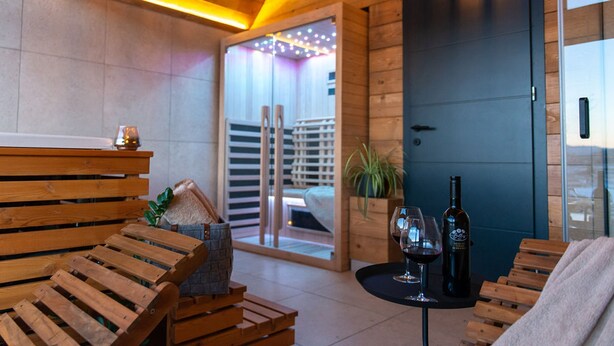 A wooden interior with a bench, a table with a wine bottle and glass, and a door. - Villa Bellis (Mrkopalj)
