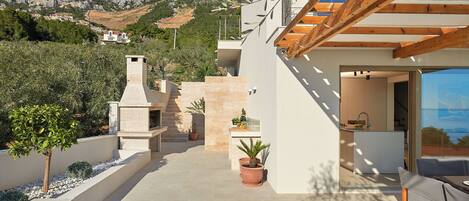 Une maison moderne avec une cheminée en pierre, des plantes en pot et une vue sur un paysage montagneux.