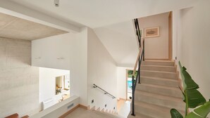 A modern staircase with a wooden handrail, a white wall with a picture, and a plant on the right. - Villa Bianka (Hvar)