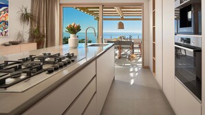 A modern kitchen with a central island, a built-in oven, and a view of the sea. - Villa Bianka (Hvar)