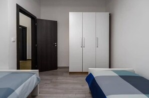 Una camera da letto con due letti singoli, un armadio e una porta che dà su un'altra stanza.