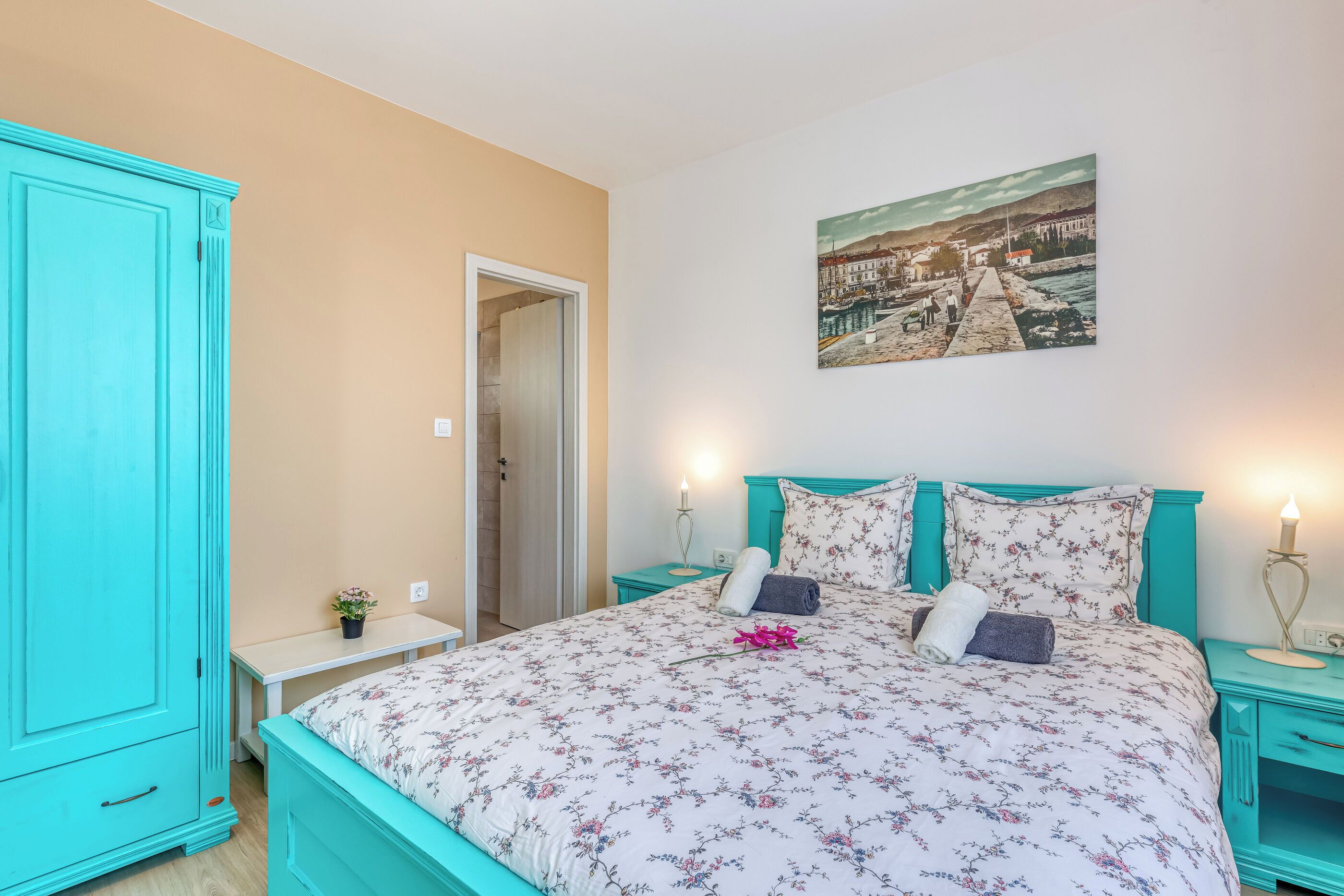 A bedroom with a bed, a nightstand, a wardrobe, and a painting on the wall.