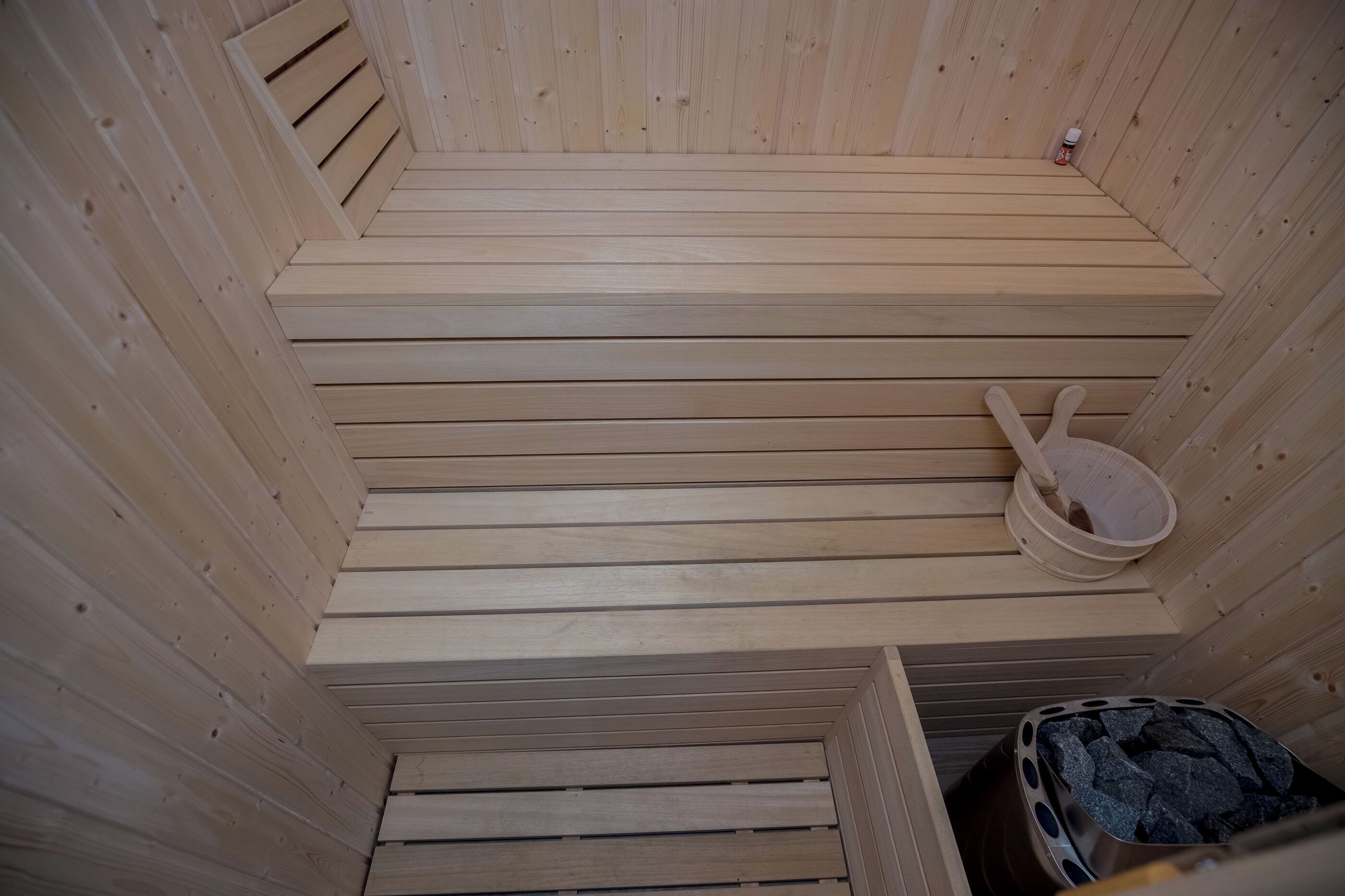 Eine Sauna mit Holzbänken und einem Eimer.