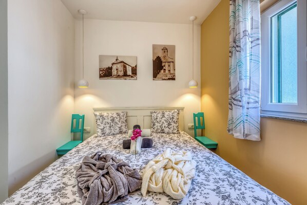 A neatly made bed with floral bedding, two wall-mounted lamps, and two framed pictures above it. - Villa Rhapsody (Bakar)