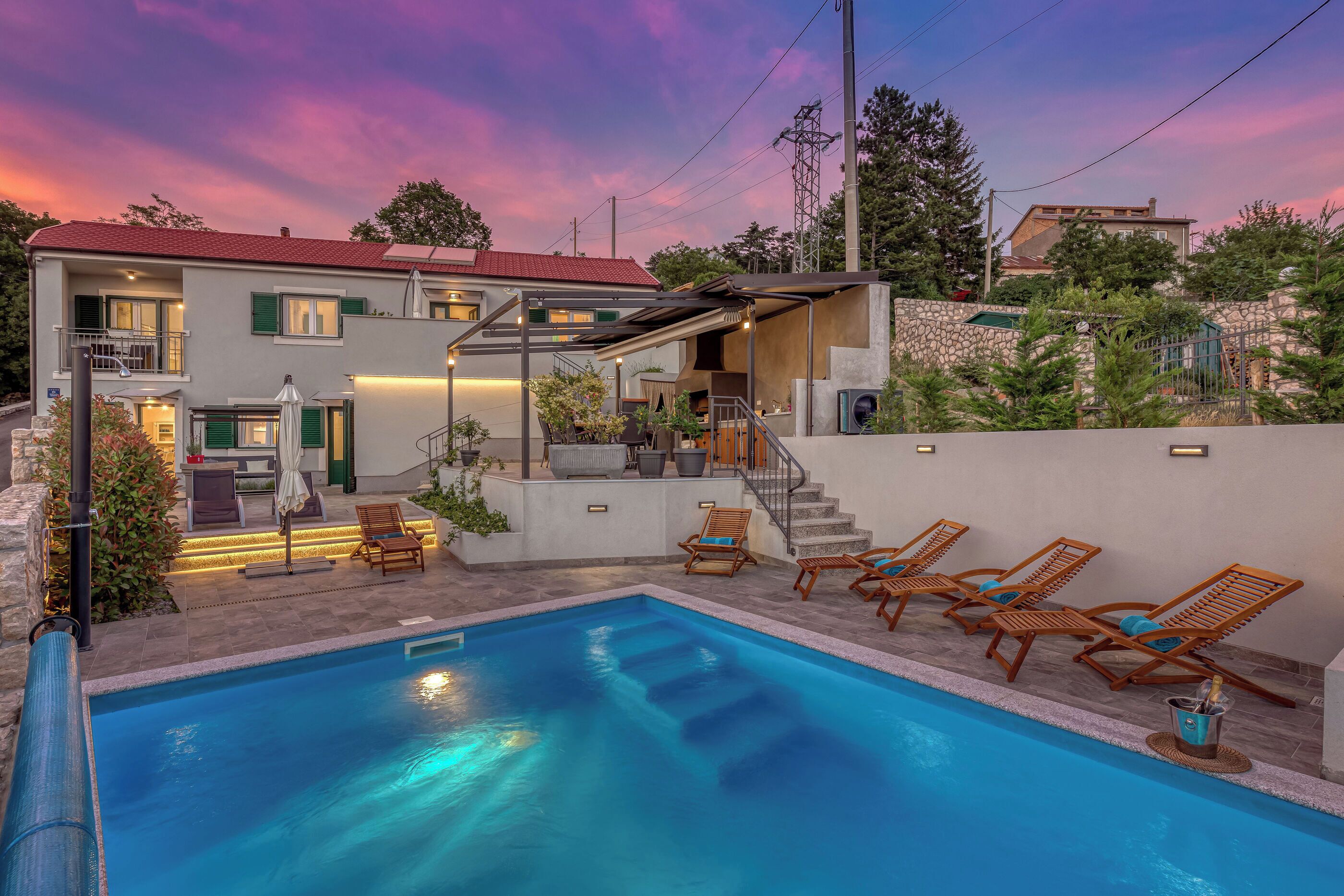 A modern house with a swimming pool, outdoor seating, and a covered patio area.