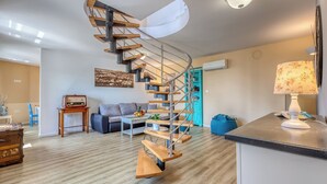 Ein modernes Wohnzimmer mit Wendeltreppe, einer Couch, einem Couchtisch und einer Lampe.