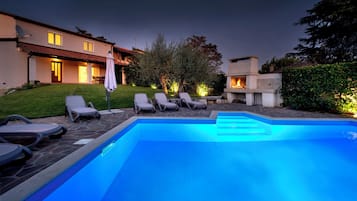 Piscina com espreguiçadeiras e área com lareira.