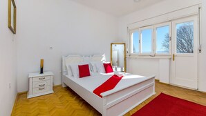 A neatly arranged bedroom with a bed, bedside table, and a window with a view. - Villa Beach Location (Split)