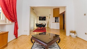A modern living room with a wooden coffee table, a dining area with a red rug, and a kitchen visible through an open doorway. - Villa Beach Location (Split)