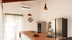 Une cuisine moderne avec un îlot central en bois, des appareils électroménagers en acier inoxydable et des luminaires suspendus.