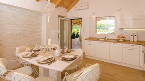 Une cuisine moderne avec des meubles blancs et un plan de travail en bois. Une table à manger, entourée de chaises blanches, est dressée pour le repas.