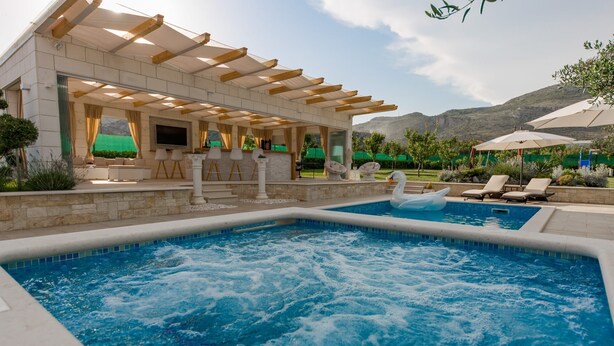 Un espace piscine comprenant un jacuzzi, des chaises longues et une pergola.