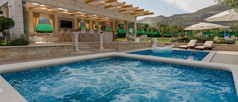 Una piscina al aire libre, una piscina climatizada, sombrillas