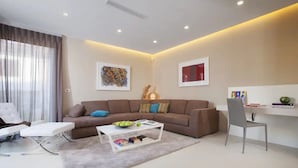 A modern living room with a brown sofa, a white coffee table, and a grey armchair. There is a white desk with a chair and a bookshelf with books and decorative items. - Villa Vera (Novigrad)