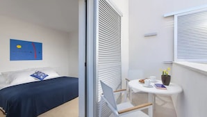 A modern hotel room with a bed, a small table with a cup, a book, and a vase with flowers. - Villa Vera (Novigrad)