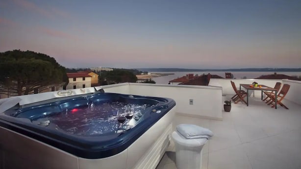 A rooftop terrace with a hot tub, a table with chairs, and a view of the sea. - Villa Vera (Novigrad)
