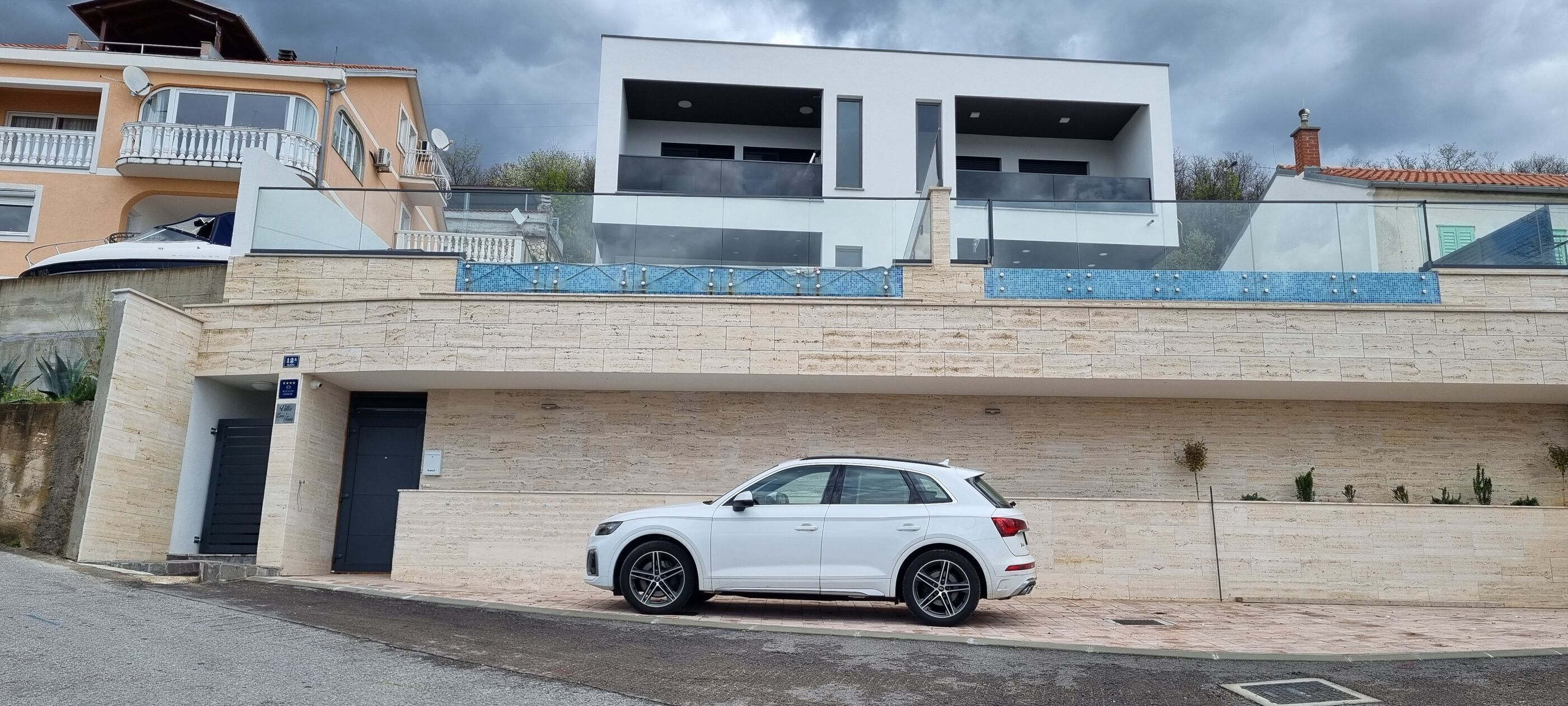 A modern two-story house with a white car parked in the driveway.