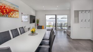 A modern dining area with a long table, black chairs, and a painting of flowers. - Villa Eva (Crikvenica)