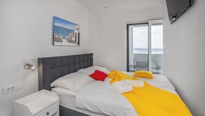 A modern hotel room with a bed, a nightstand, a painting, and a large window offering a view. - Villa Eva (Crikvenica)