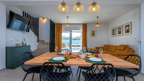 Un comedor moderno con una mesa de madera, sillas negras y un televisor montado en la pared.