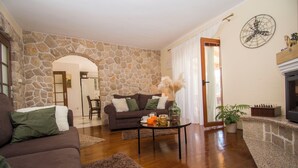Una sala de estar con pared de piedra, chimenea y comedor.
